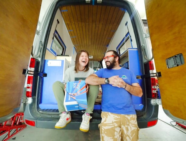 a man and woman standing in a van with surfboards