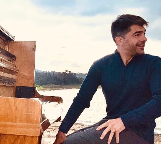 a man sitting on a bench in front of a piano