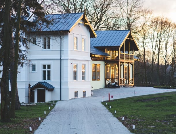 A stately white house surrounded by trees and lush grass