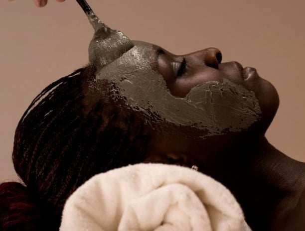 a woman is getting a facial mask with a spoon