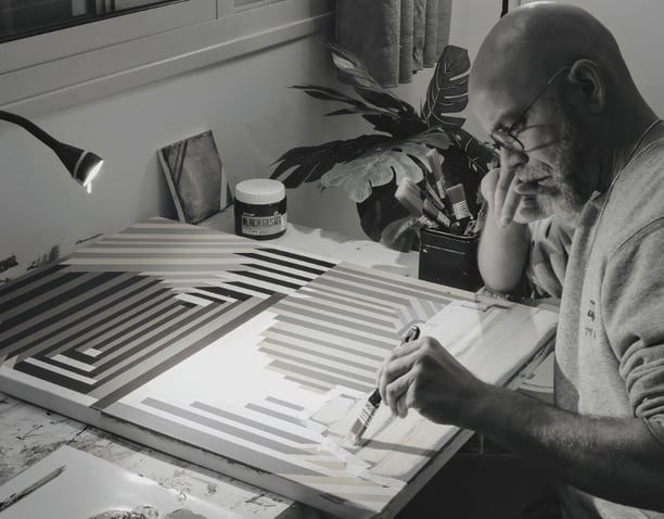Artist Yonathan Niv working in his studio on abstract paintings and print layouts, surrounded by ori