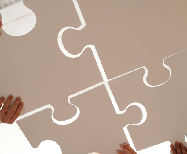 plusieurs personnes qui font un Puzzle montrant l'unité et l'objectif d'entraide de Subvasso