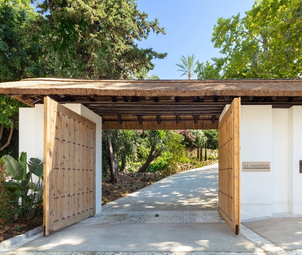 Entrance gates of Villa La Gratitud, framed by manicured greenery.