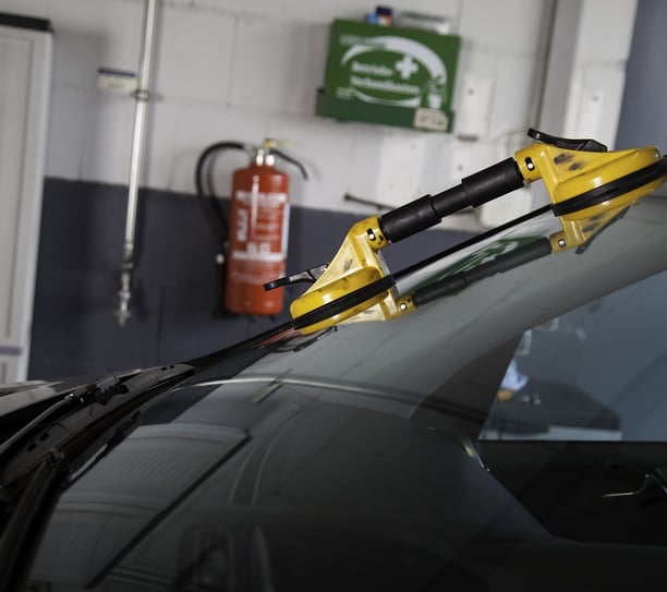 a car with a yellow handlebarb in the back ground at fix collision center fixing its broken glass