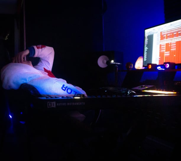 a man is slumped over in a chair in the dark. With a computer screen on.