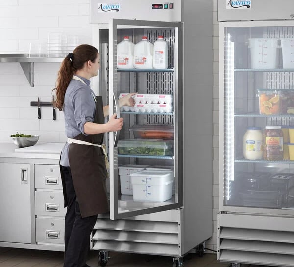 a woman in a apron and aprons is standing in front of a refrigerator