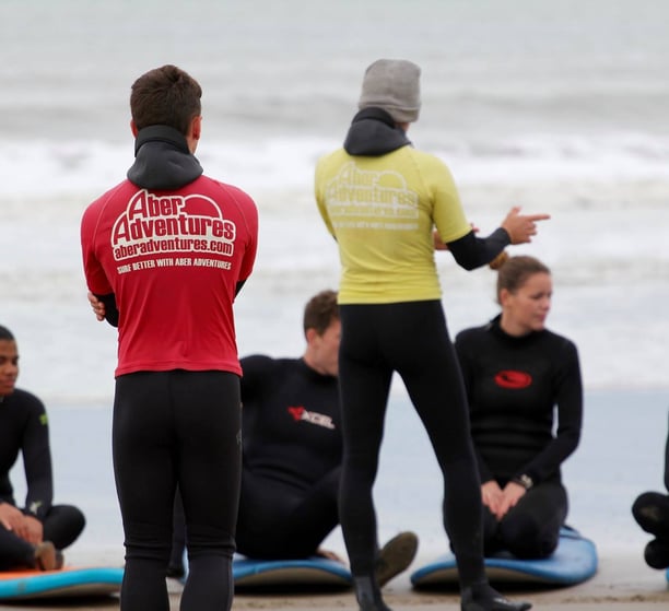 Two surf coaches instructing a group for a beginner surf lesson