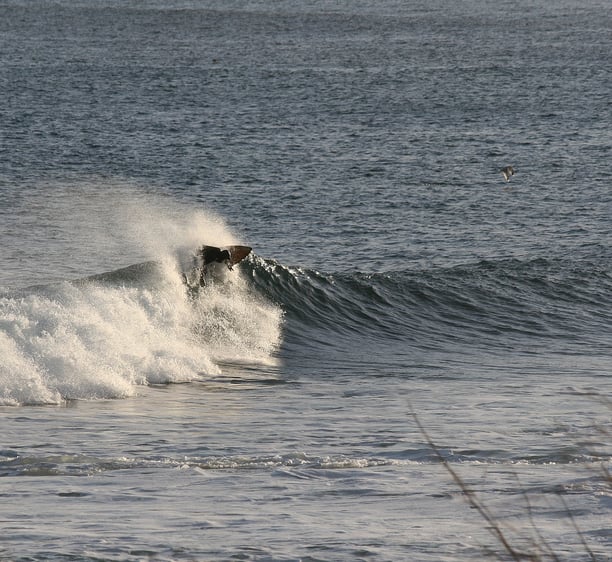 A surfer hitting the lip backside of a sunlit wave.