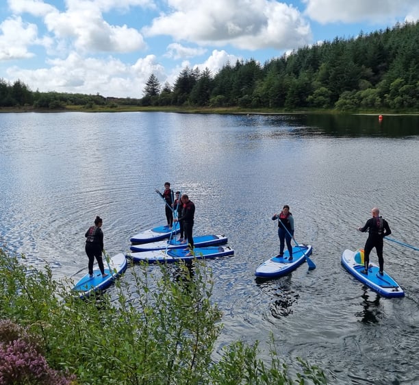 A stand up paddle board group hiring equipment on Llyn Pendam Lake