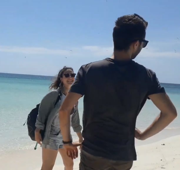 a man and woman standing on a beach