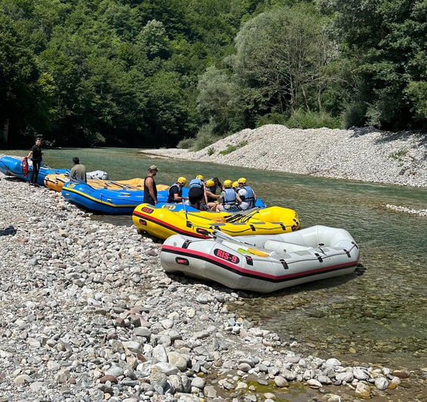 Rafting boats and adventurers preparing on the beach by Neretva River