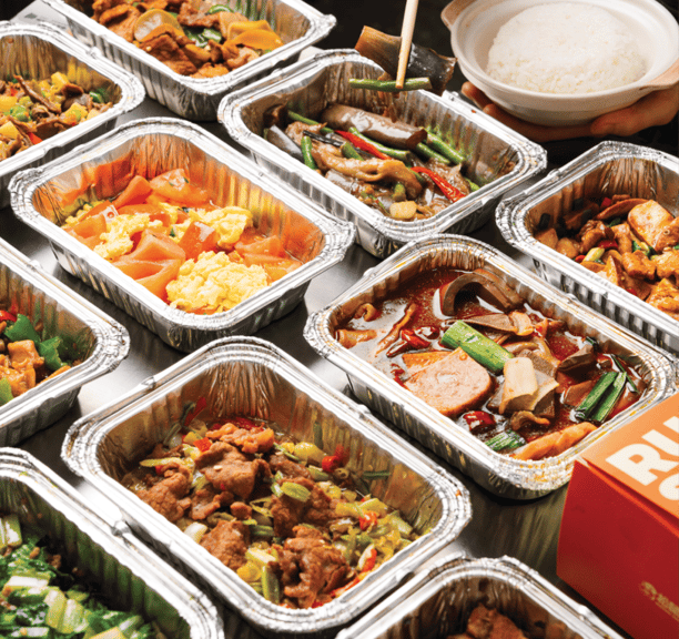 a table with many trays of food and a person holding a spoon