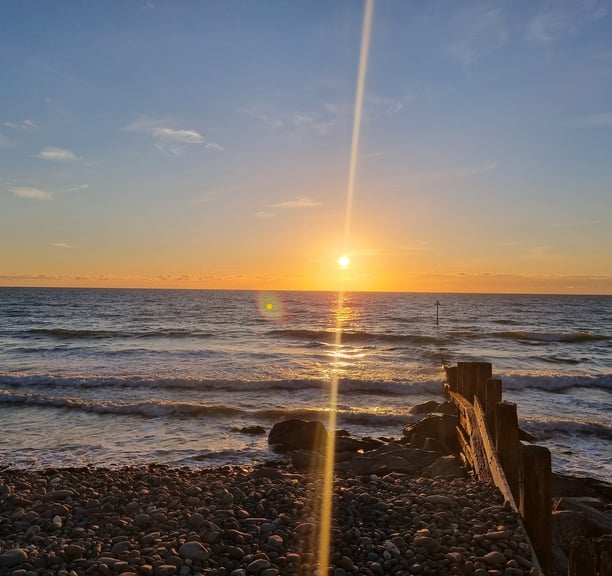 A golden sun just abobot to set into the sea at Ynyslas with a wooden groyne running into the sea.