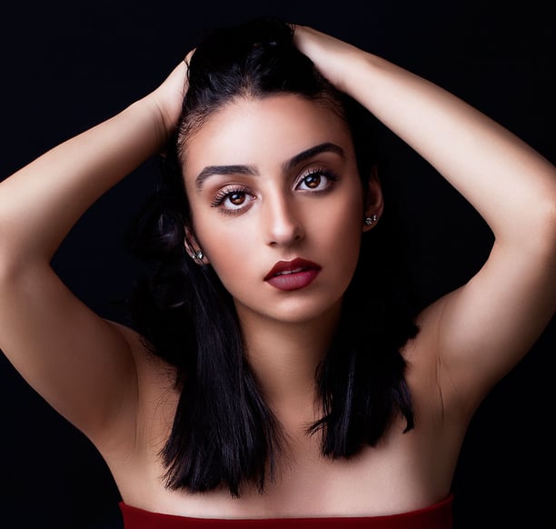 a beautiful brown eyed girl with tanned skin, plump auburn lips, pulling her hair back and posing like a model