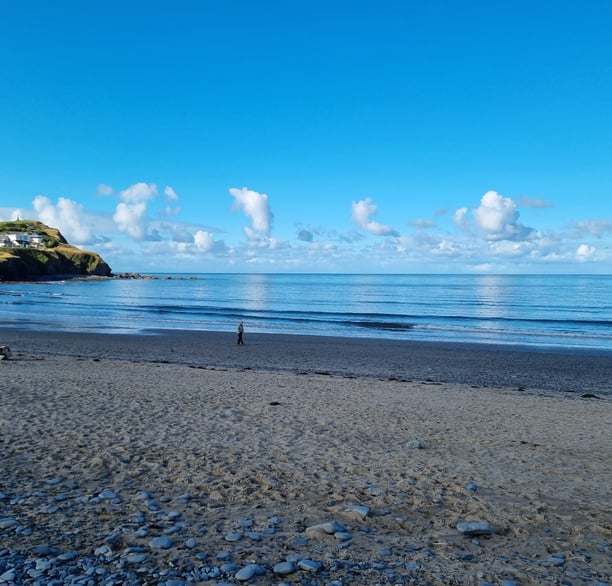 Borth beach with smooth glassy sea blue sky and fluffy clouds