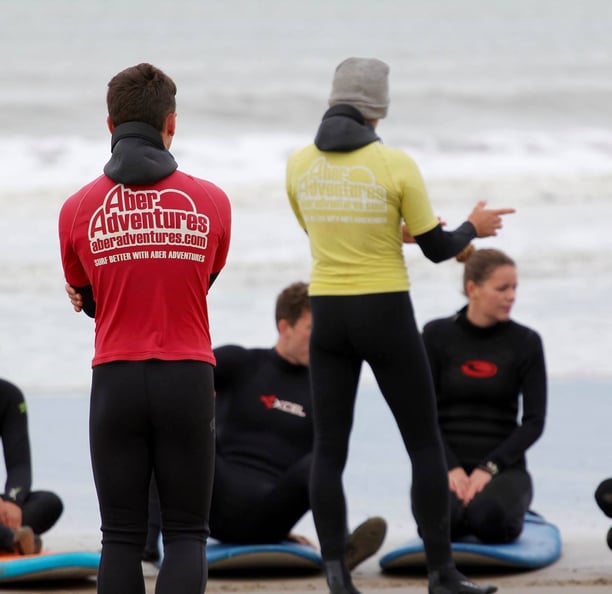 two surf coaches giving a safety brief while group listens.