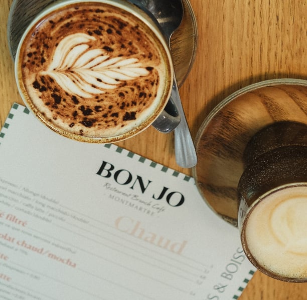 alt="Brunch coffee at Bon Jo café in Montmartre, Paris – artisan latte with menu featuring homemade drinks and breakfast spec