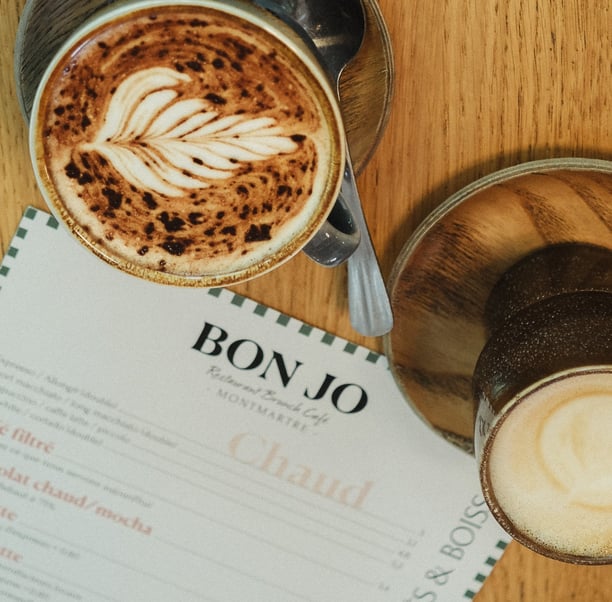 alt="Brunch coffee at Bon Jo café in Montmartre, Paris – artisan latte with menu featuring homemade drinks and breakfast spec