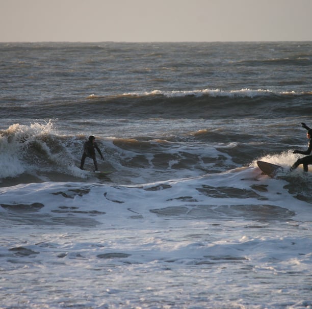 Two surfers in wintery Borth riding waves