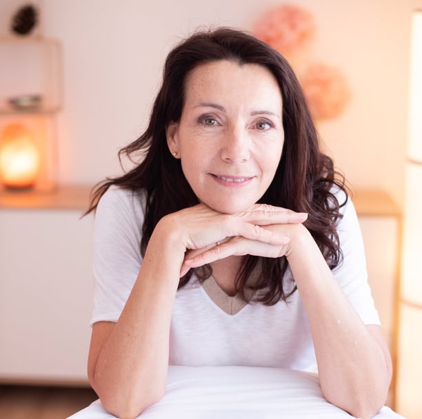 a woman sitting on a chair with her hands on her chin