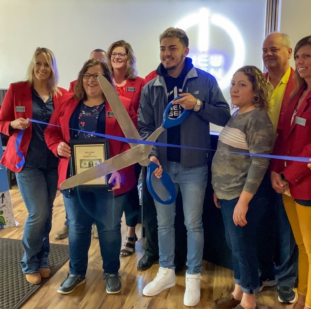 a group of people holding scissors and cutting a ribbon