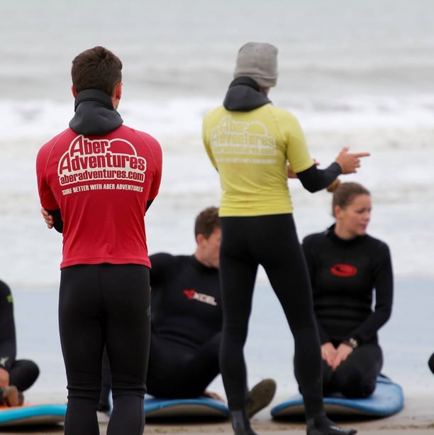 two surf coaches giving a safety brief while group listens.