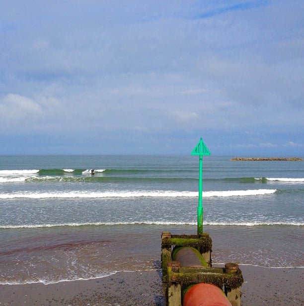 A surfer riding a clean summer time wave in Borth