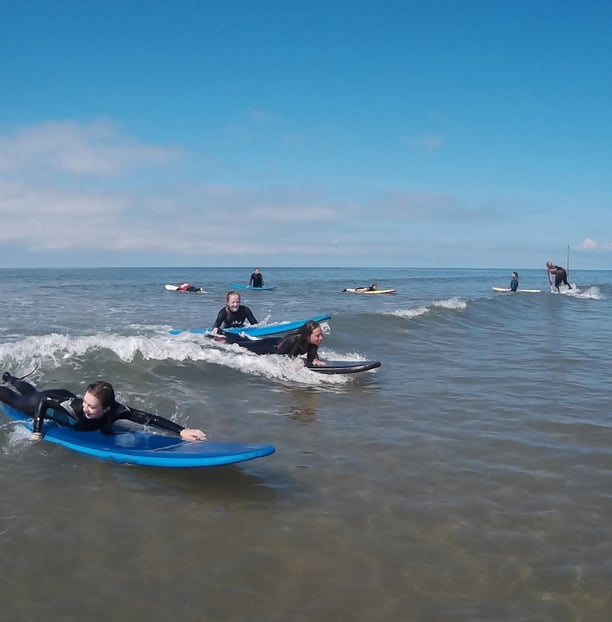 Two surfers paddling for a wave during Ysgol Tywyn activities day.