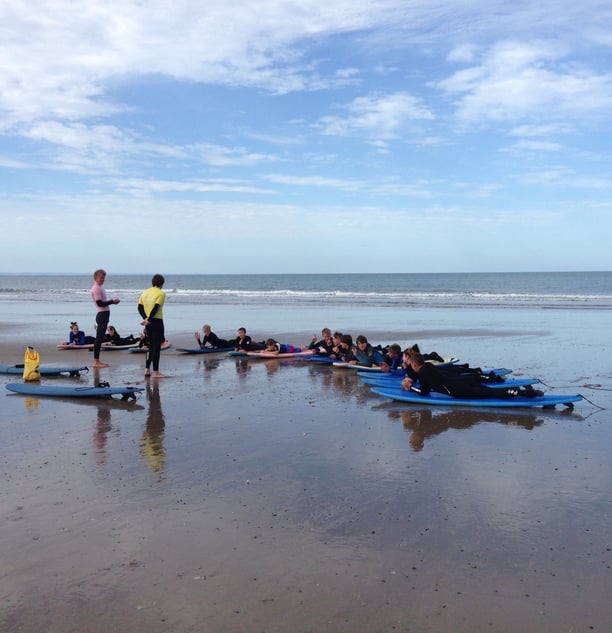 Two surf coaches delivering a surf safety brief to a large group on the beach