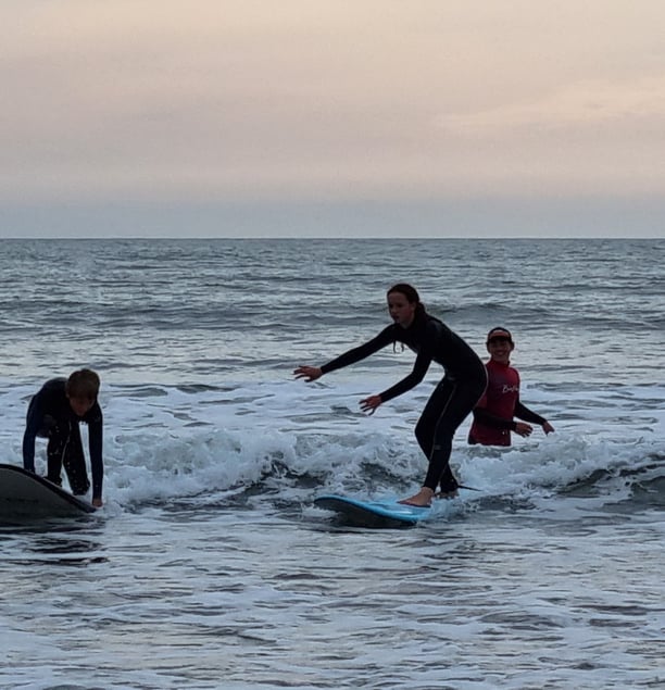 Two surfers riding the smae small wave with a surf coach watching