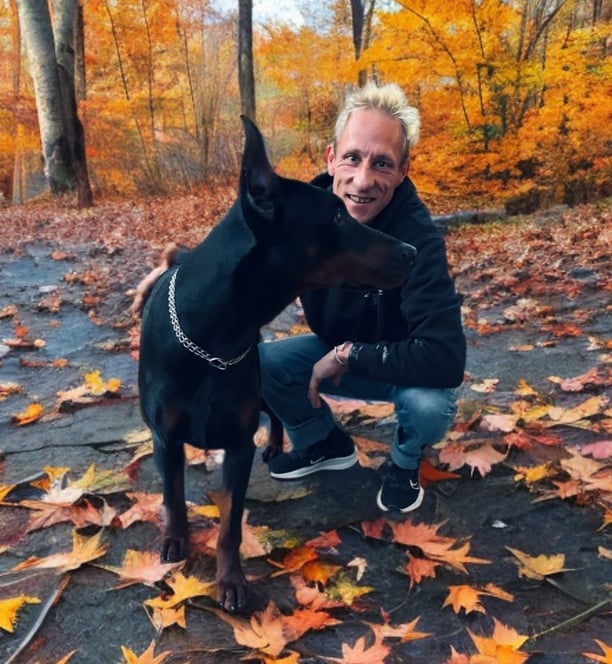a man with blonde hair and a dog in a park