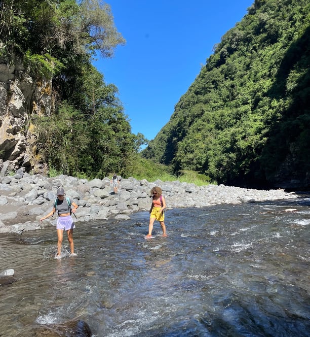 two people standing in a river with a mountain in the background