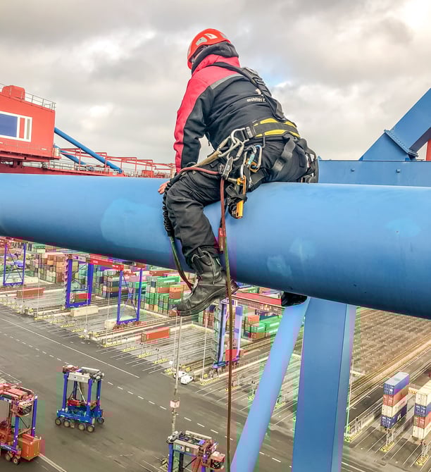 a man in a helmet and safety gear on a crane