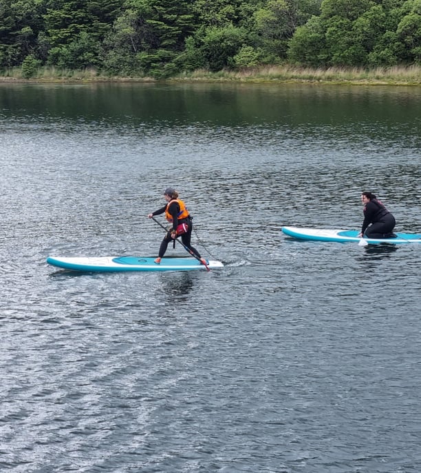 A paddle board coach demonstrating a step back turn to a student