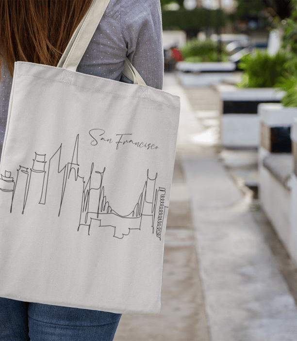 a woman walking down a sidewalk with a tote bag