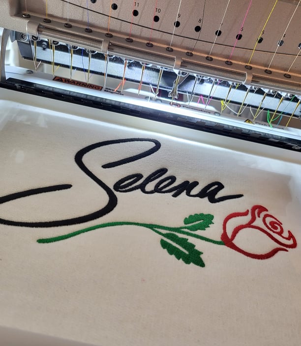 Embroidery machine stitching a floral and script logo design – high-quality embroidery service by St