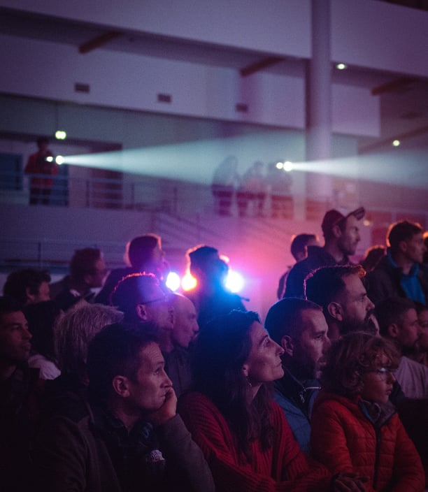 Public captivé devant une projection, éclairé par des faisceaux lumineux en ambiance immersive