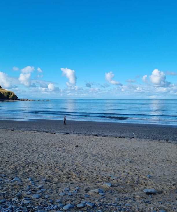 Borth Beach with calm glassy seas, blue skies and cumulus clouds