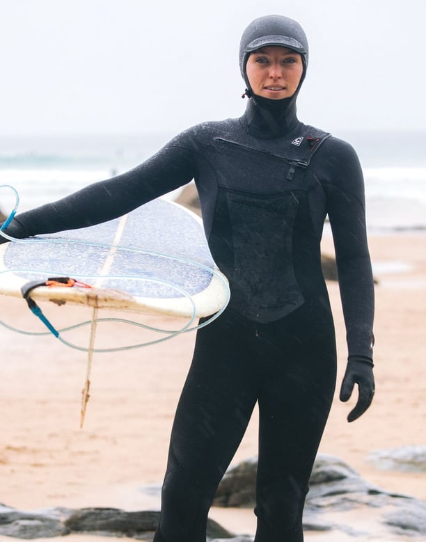 A female surfer in full winter wetsuit equipment 