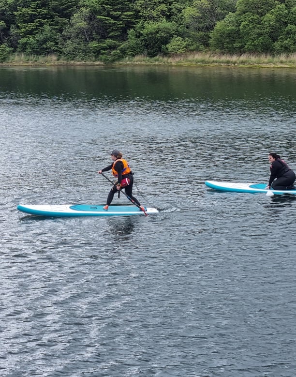 A paddle board coach demonstrating a step back turn to a student