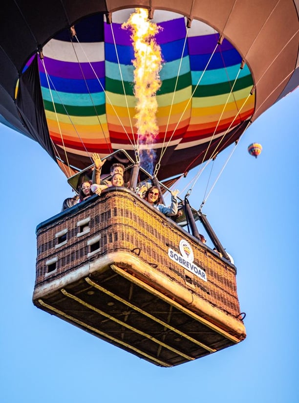 Voo de balão compartilhado repleto de família feliz sobrevoando Praia Grande-SC