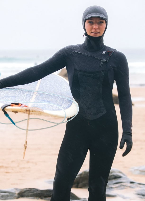 A female surfer wearing full winter wetsuit equipment