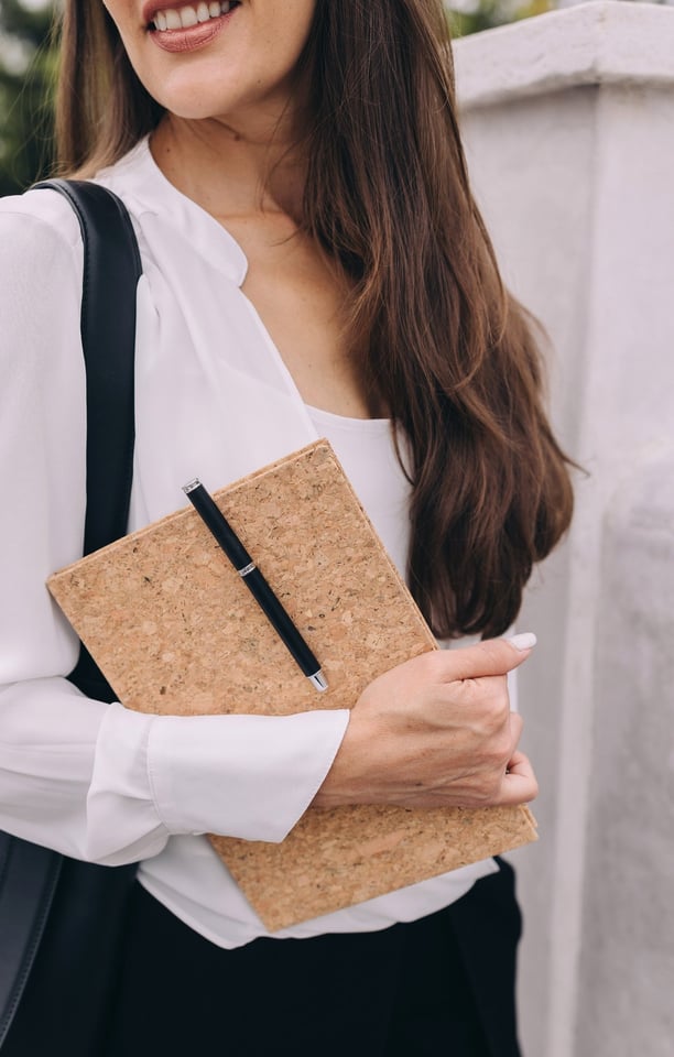 a woman in a white blouse and black pants carrying a notebook with pen