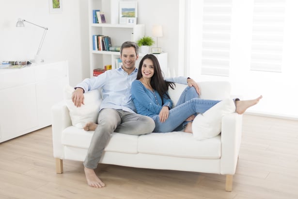 a man and woman sitting on a couch enjoying their air conditioning