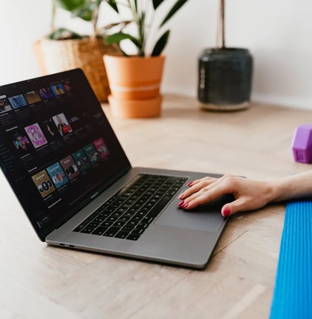 a woman sitting on a yoga mat with a laptop