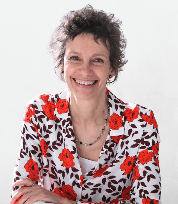 Une femme souriante, aux cheveux bruns et bouclés, elle porte un blazer fleuri, elle est sophrologue