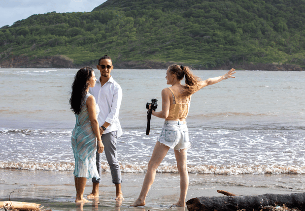 a man and woman standing on a beach while Solana photographs