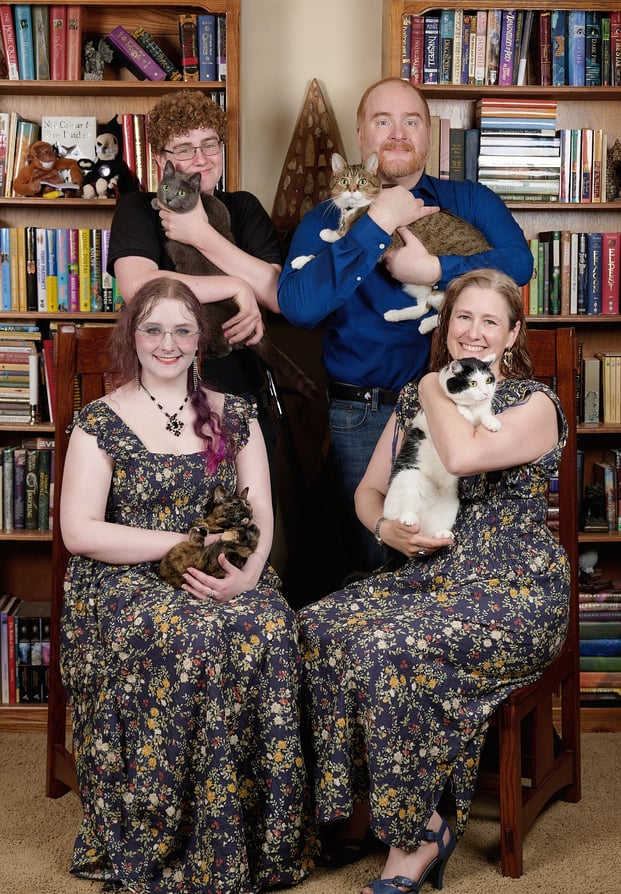 a family portrait of parents and kids with four cats on their arms
