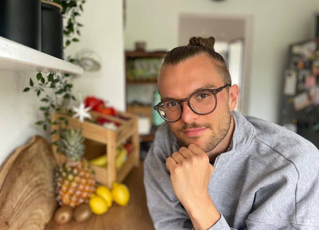 ein mann mit Brille und bart, der in einer Küche vor Gemüse und Obst steht