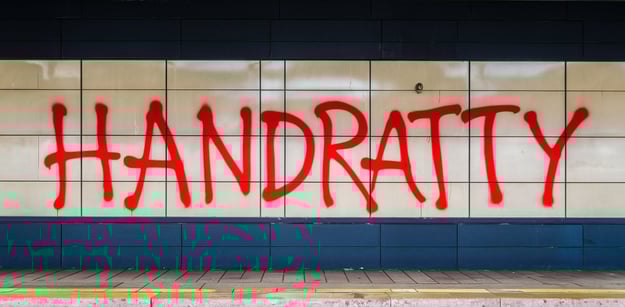 a subway station with “HANDRATTY” graffiti on the wall